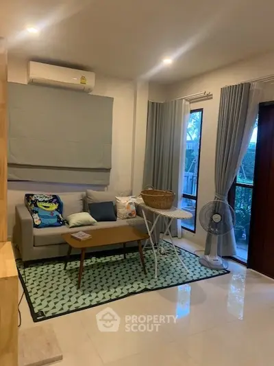 Cozy living room with modern decor, featuring a comfortable sofa, stylish coffee table, and large windows for natural light.