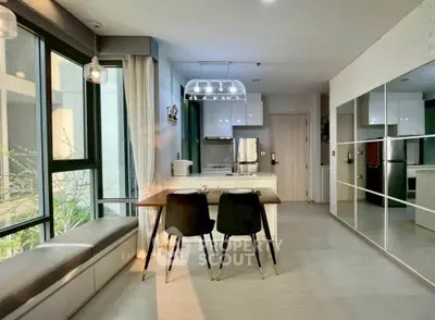 Modern kitchen with open layout, sleek cabinetry, and stylish dining area in a bright, sunlit apartment.