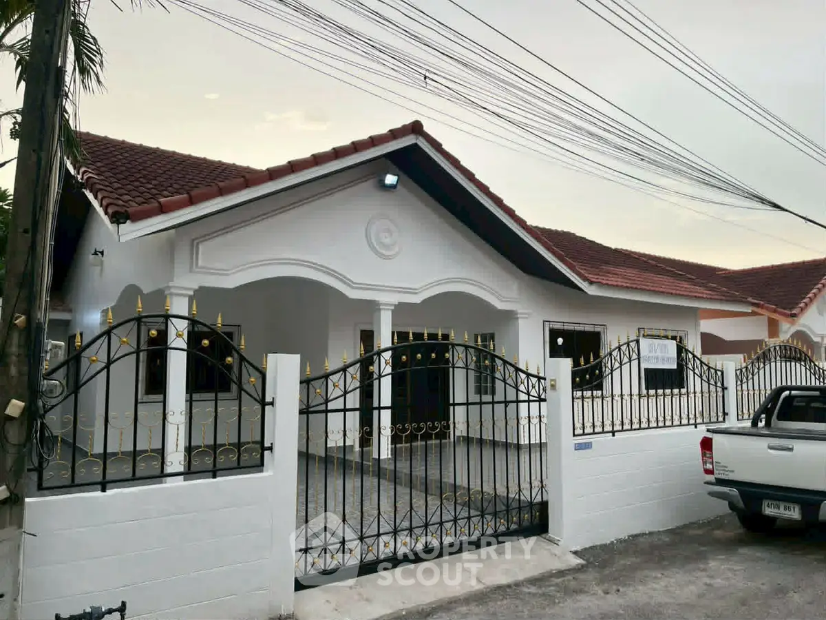 Charming single-story house with gated entrance and red-tiled roof, perfect for family living.