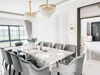 Luxurious dining room with elegant marble table and plush chairs, featuring modern chandeliers and natural light.