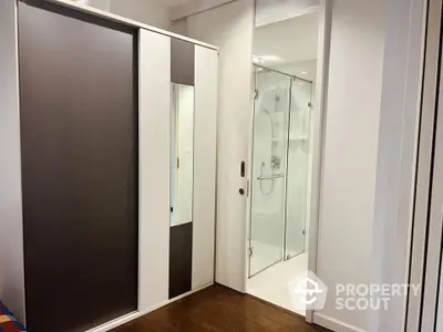 Modern apartment interior with sleek wardrobe and glass shower enclosure