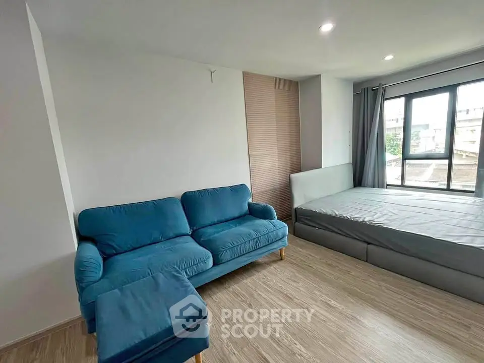 Modern studio apartment with cozy blue sofa and large window view
