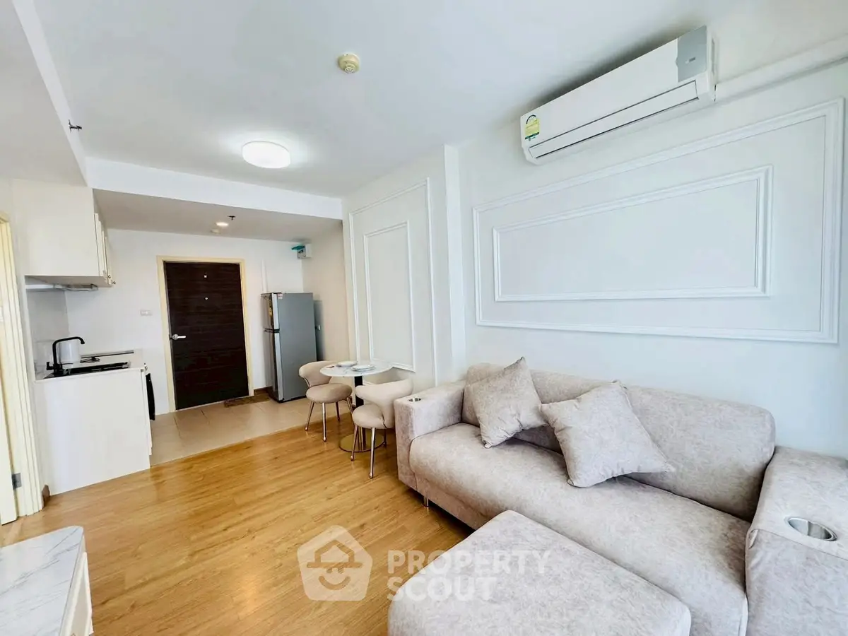 Modern living room with cozy sofa and open kitchen layout in bright apartment.