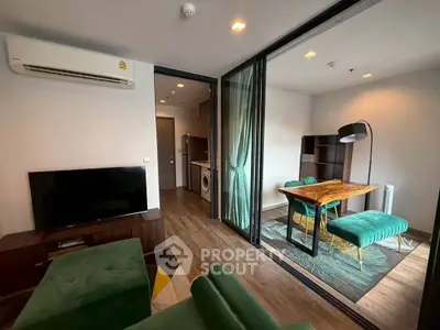 Modern living room with green sofa, TV, and dining area with stylish table and chairs in open layout.