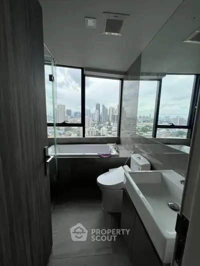 Modern bathroom with city view, featuring sleek fixtures and large windows.