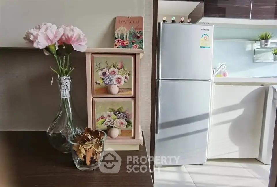 Charming kitchen corner with modern fridge and floral decor, perfect for cozy living.