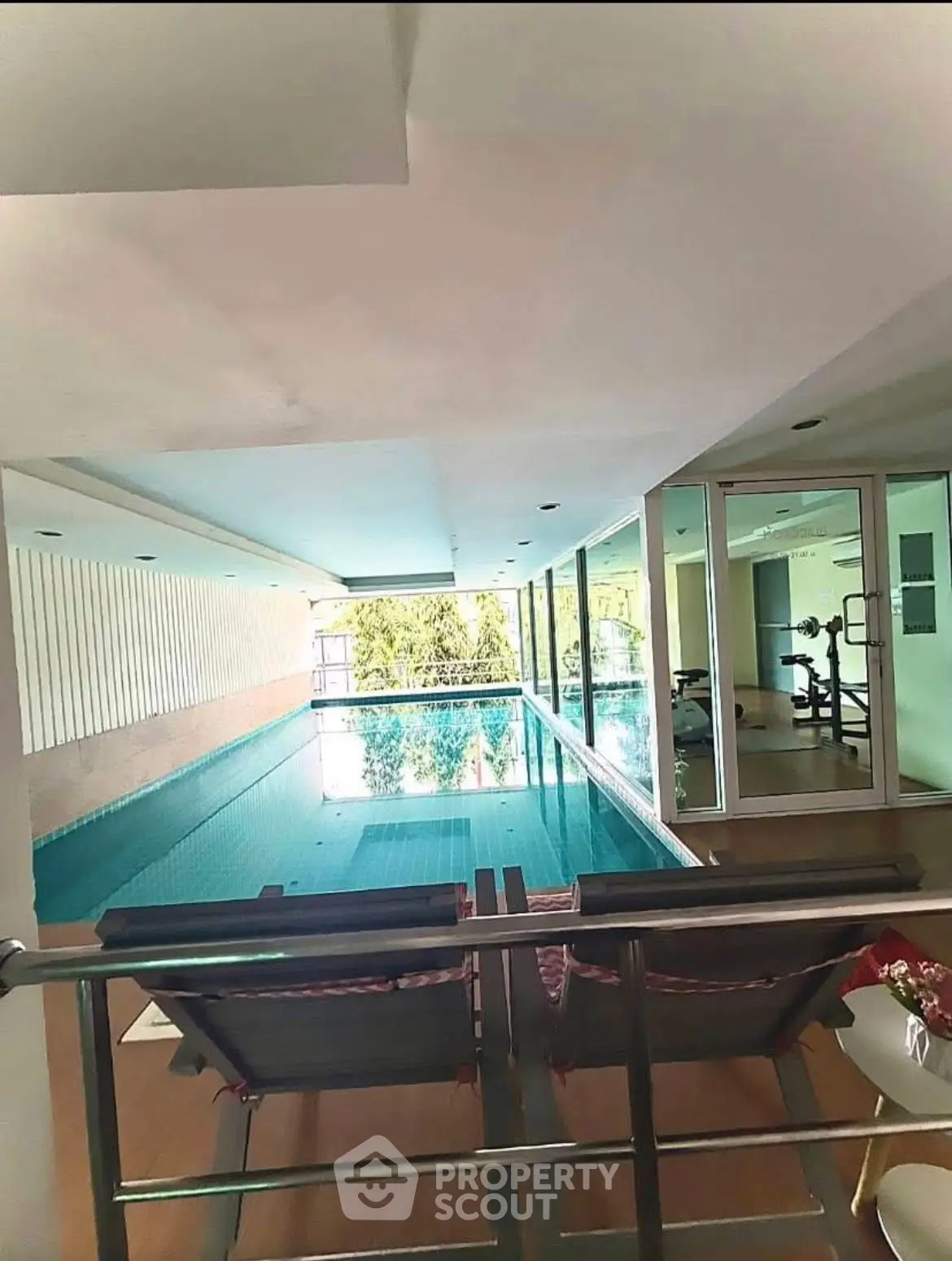 Luxurious indoor pool with adjacent gym in modern residential building.