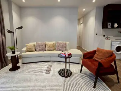 Modern living room with stylish furniture and washing machine in corner