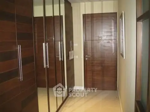 Stylish hallway with wooden doors and mirrored closets in modern home.