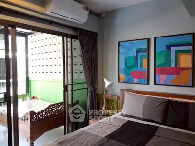 Stylish bedroom with balcony, featuring modern art and cozy furnishings for urban living.