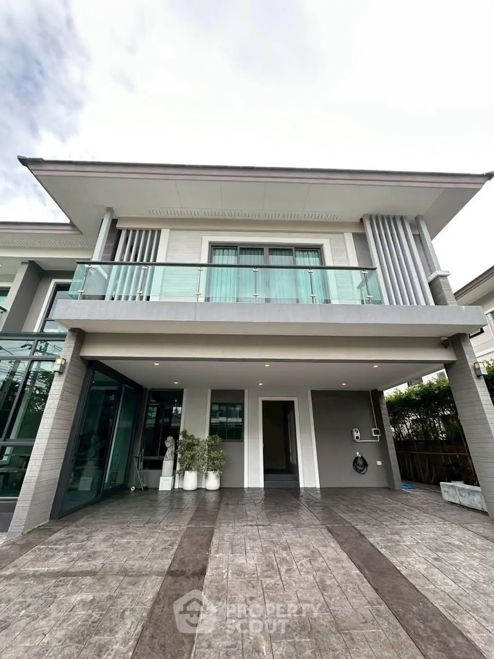 Modern two-story house with spacious driveway and glass balcony