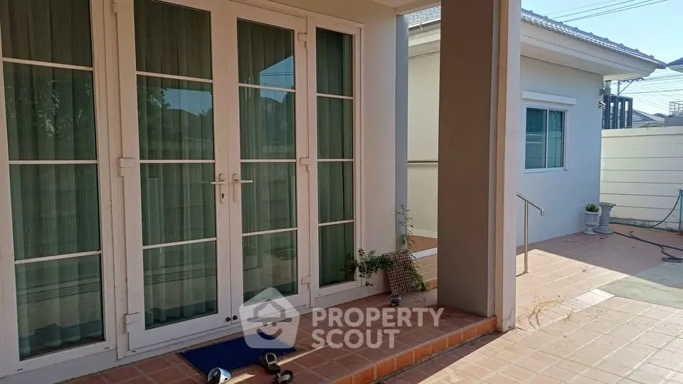 Charming residential entrance with elegant French doors and spacious patio area.