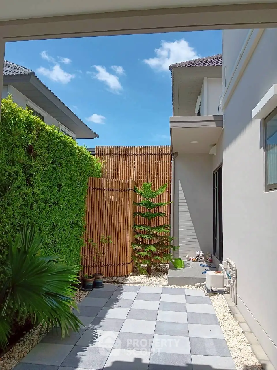 Charming modern home exterior with lush greenery and bamboo privacy fence, perfect for tranquil living.