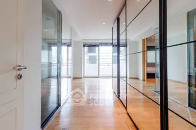 Spacious modern living room with floor-to-ceiling windows and sleek wooden flooring.