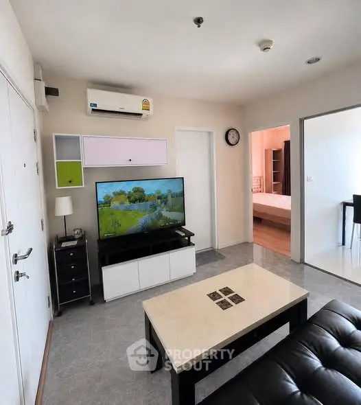 Modern living room with sleek furniture and wall-mounted TV in a cozy apartment setting.
