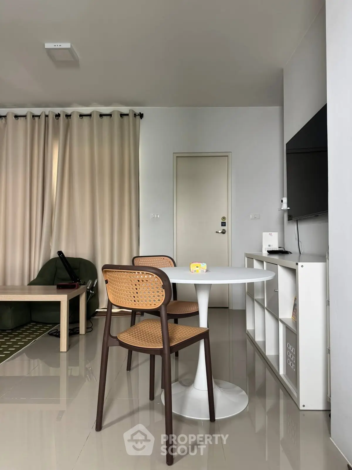 Modern living room with sleek furniture and neutral tones, featuring a stylish dining area.