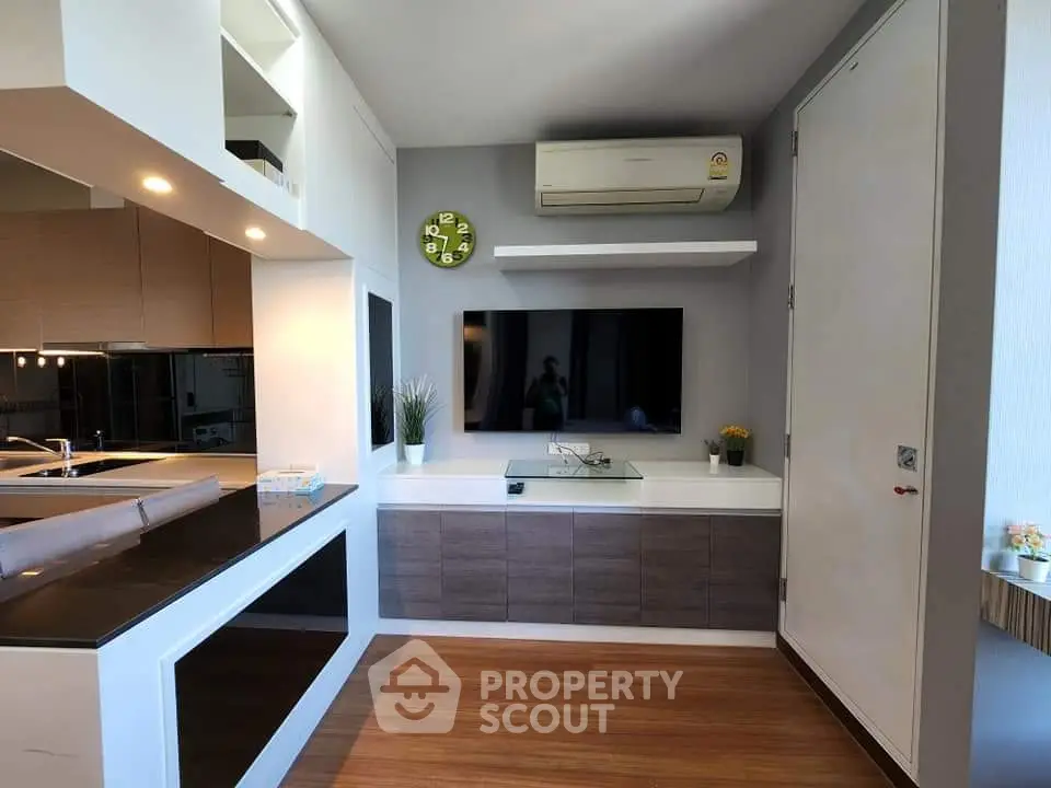 Modern living room with sleek TV setup and stylish kitchen area