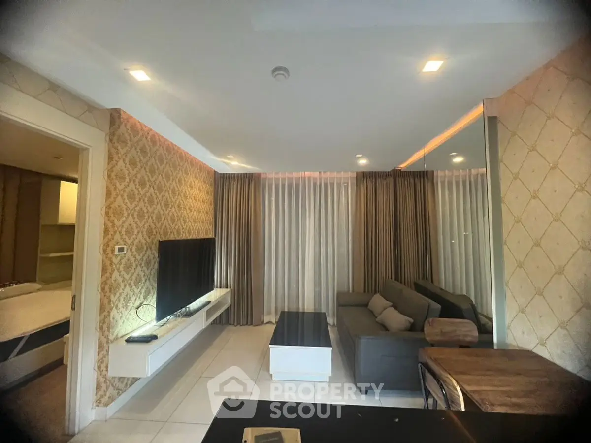 Modern living room with stylish decor and large TV, featuring elegant curtains and cozy seating area.