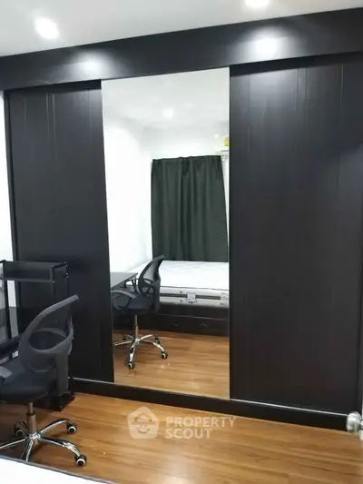 Modern bedroom with mirrored sliding closet doors and sleek office chairs.