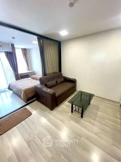 Modern apartment with cozy living room and adjacent bedroom, featuring sleek wooden flooring and stylish furnishings.