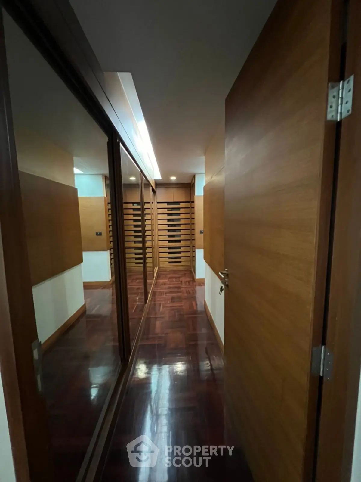 Luxurious hallway with wooden flooring and mirrored closet doors in a modern home.