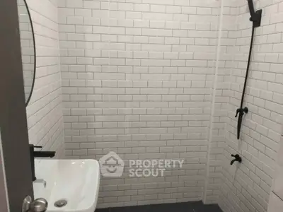Modern minimalist bathroom with white subway tiles and sleek black fixtures.