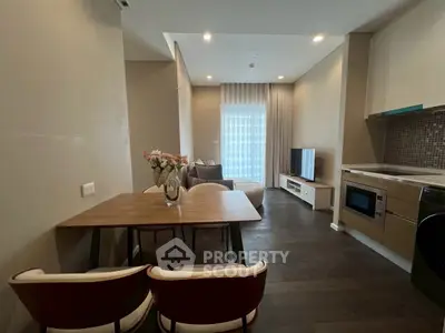 Modern open-layout living room with dining area and sleek kitchen appliances.