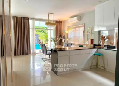 Spacious modern kitchen with open layout and elegant dining area, featuring large windows and stylish decor.