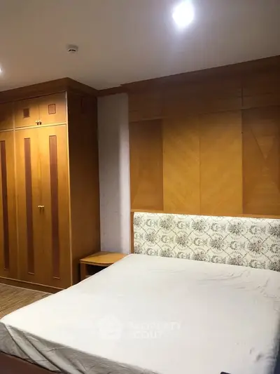 Spacious bedroom with wooden wardrobe and elegant headboard, perfect for a cozy retreat.