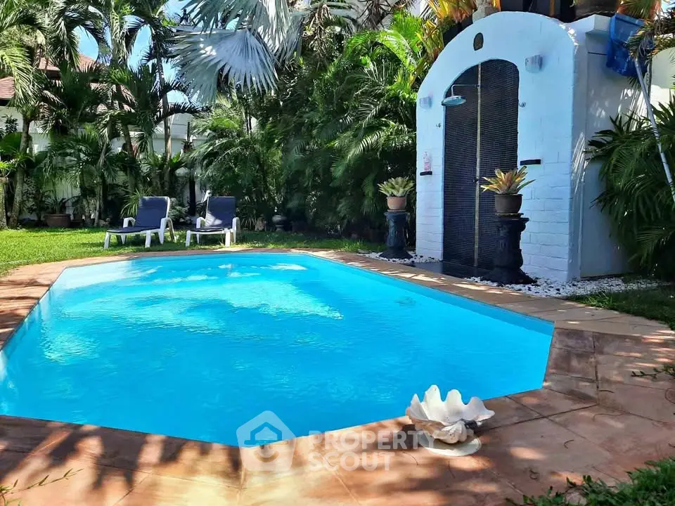Luxurious private pool surrounded by lush greenery and elegant outdoor shower, perfect for relaxation.