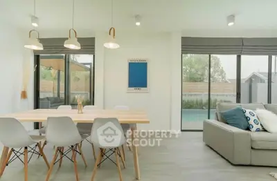 Modern living room with stylish dining area and pool view, featuring contemporary furniture and large windows.