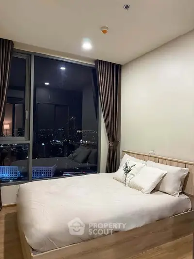 Modern bedroom with city view, featuring large windows and elegant decor.