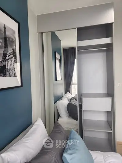 Modern bedroom with stylish decor and built-in closet, featuring elegant blue accents and cozy pillows.
