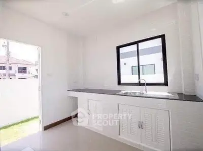 Bright minimalist kitchen with sleek countertops and ample natural light.