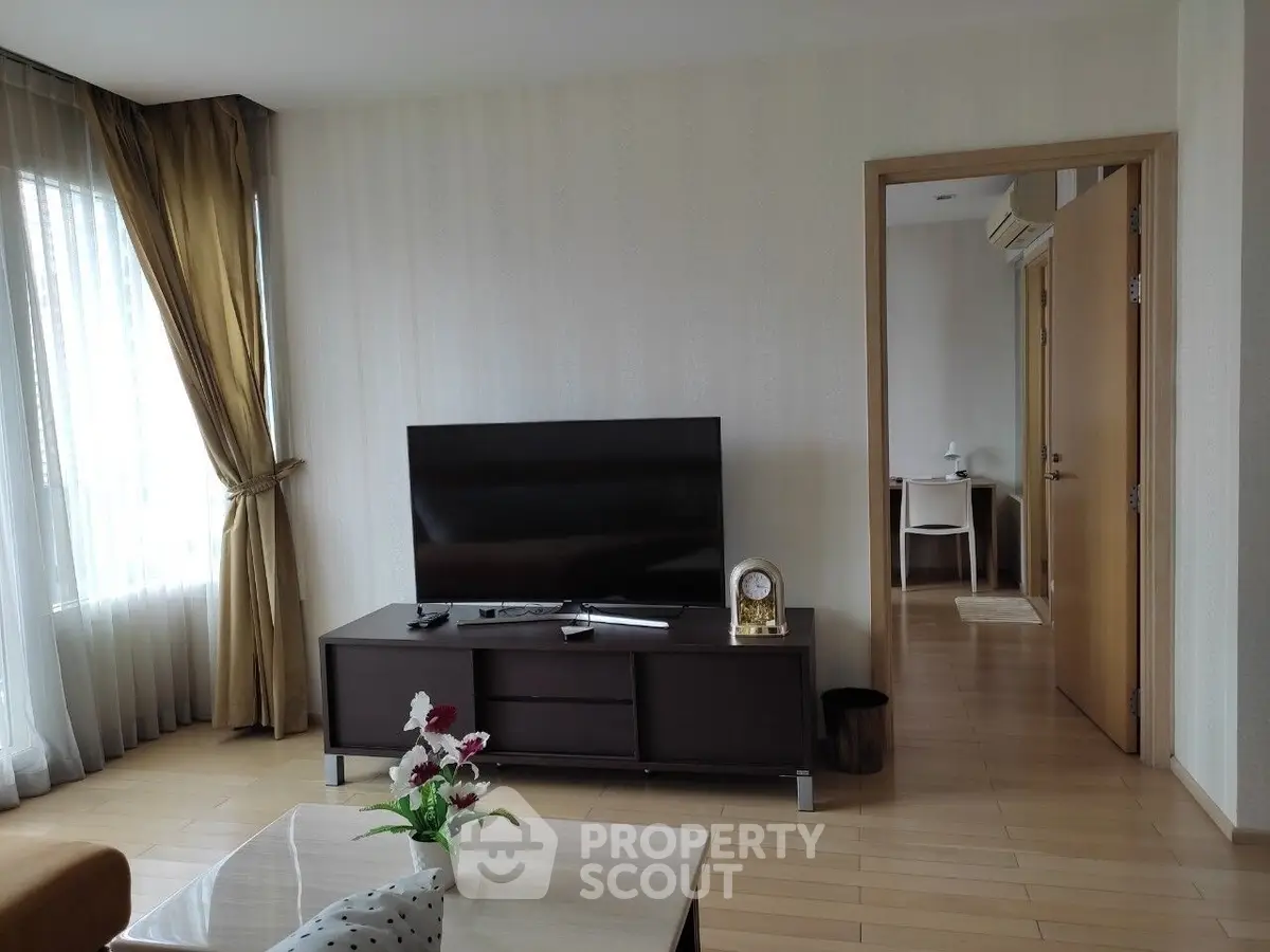 Spacious living room with modern decor and large TV, perfect for relaxation and entertainment.
