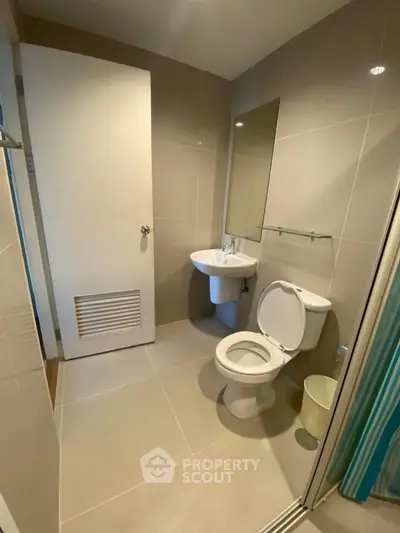 Modern bathroom with sleek fixtures and neutral tiles, featuring a compact design.