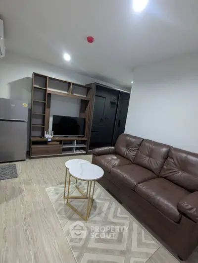 Modern living room with leather sofa, TV unit, and sleek refrigerator in a cozy apartment.
