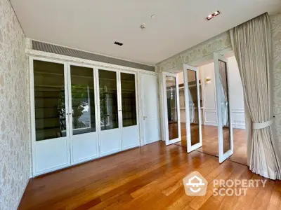 Elegant room with wooden flooring and glass doors leading to a bright space, ideal for modern living.