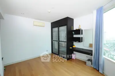 Spacious bedroom with wooden flooring and city view