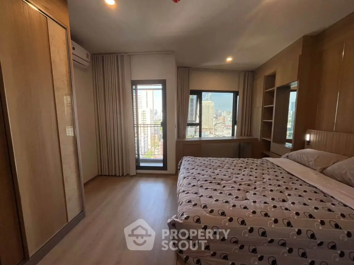 Spacious bedroom with city view, modern furnishings, and ample natural light in a high-rise apartment.