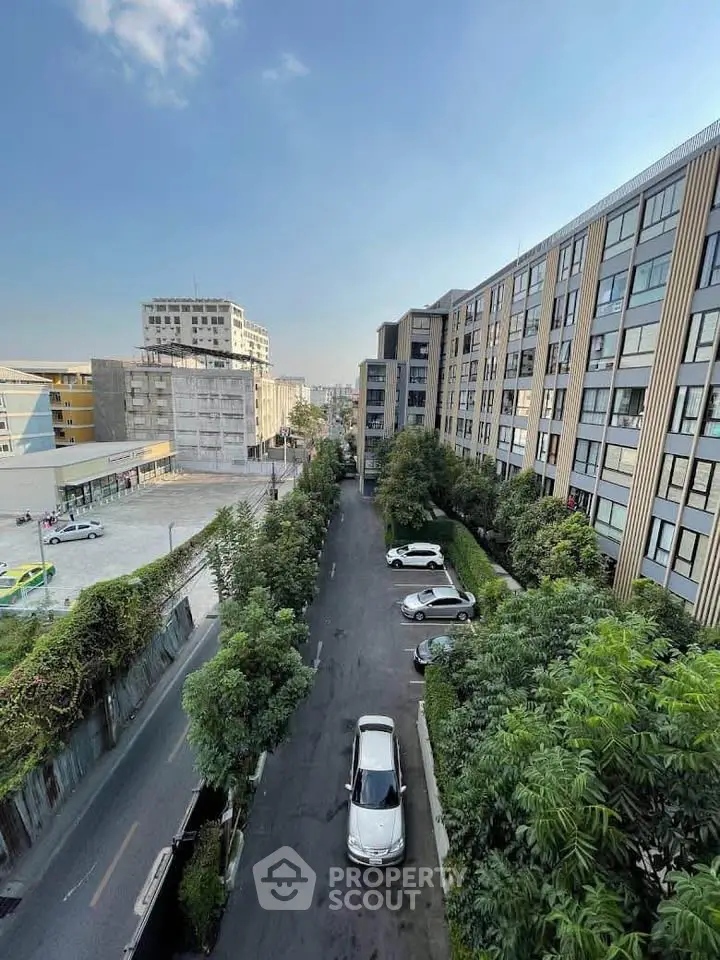 Modern urban apartment complex with lush greenery and parked cars