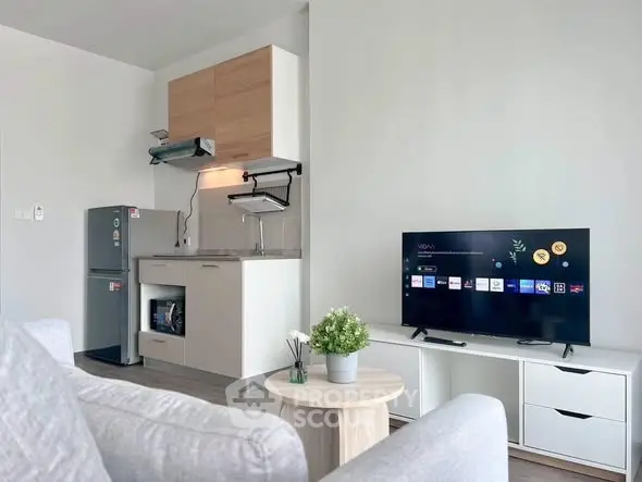Modern living room with sleek kitchen, featuring a smart TV and stylish decor in a cozy apartment.