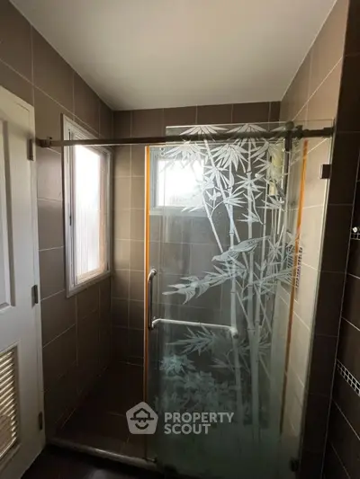 Modern bathroom with frosted glass shower door and tiled walls
