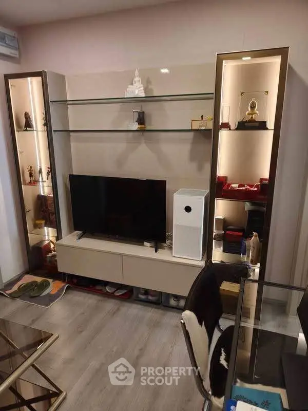 Modern living room with sleek TV unit and glass shelves, showcasing stylish decor and contemporary design.