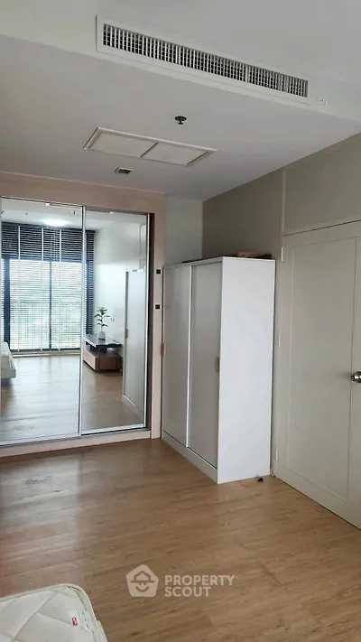 Modern bedroom with mirrored wardrobe and wooden flooring, offering a sleek and spacious design.
