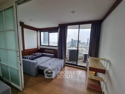 Modern living room with city view and balcony access in high-rise apartment.
