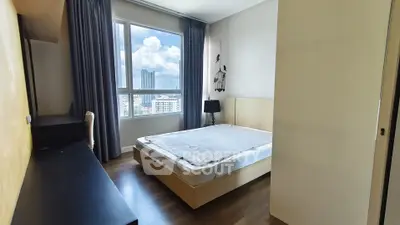 Spacious bedroom with large window offering stunning city views, modern furnishings, and ample natural light.