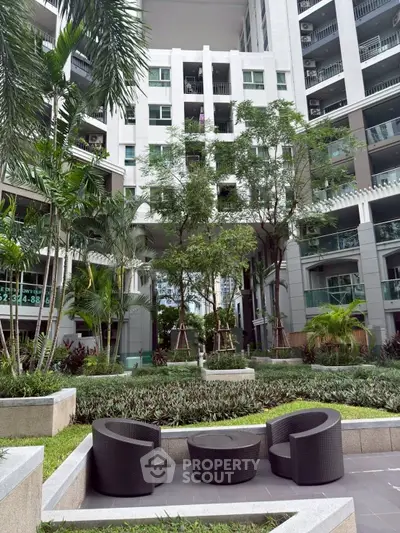 Modern apartment building with lush garden and stylish outdoor seating area.