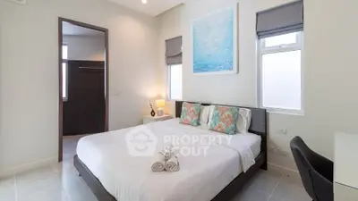 Modern bedroom with elegant decor and natural light, featuring a comfortable bed and stylish artwork.