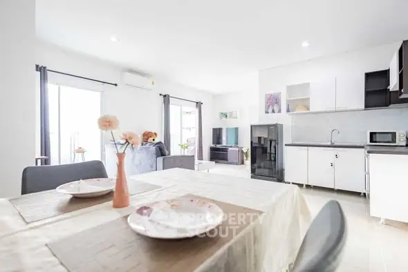 Bright modern living room with open kitchen and dining area, featuring stylish decor.